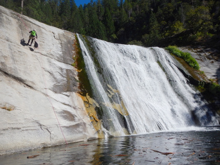 Judit rappeling into a pool packed with floating logs
